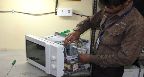 Srinivas Enterprises technician repairing a microwave oven